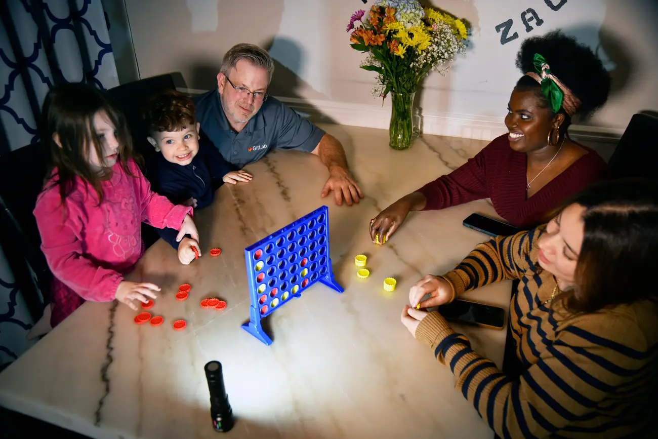 A family together at a table, lit by a Lumen Force flashlight during a power outage.